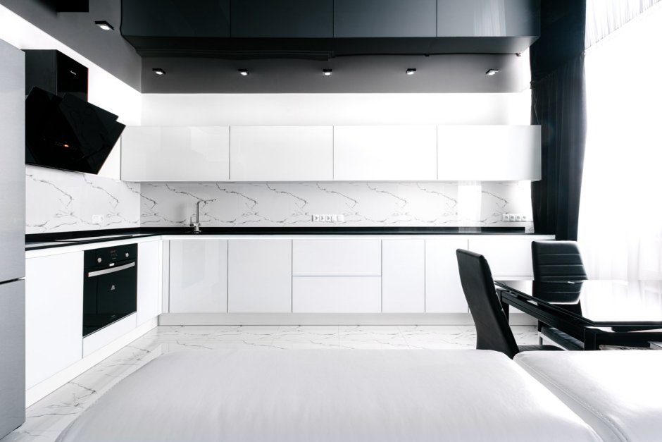 Белая кухня с чёрной столешницей и белым фартуком