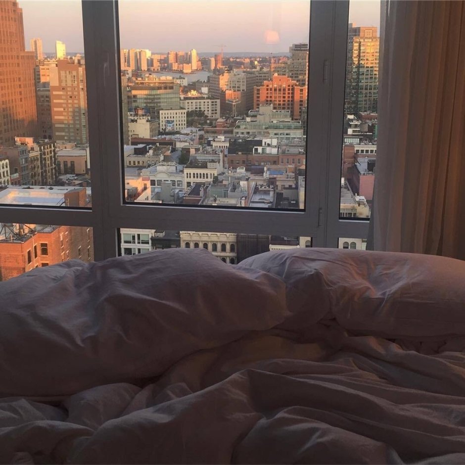 Кровать и окно на вид город
