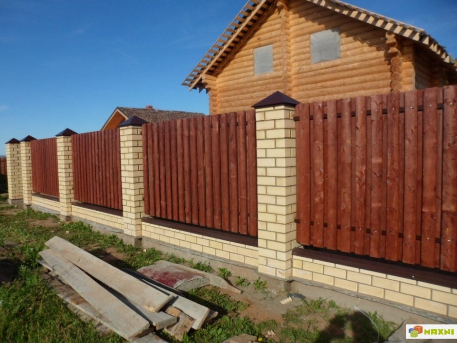 Деревянный забор между кирпичными столбами