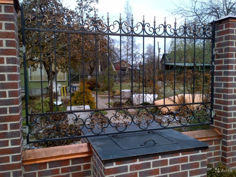 Кованый забор между кирпичными столбами
