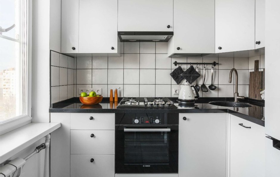 Белая кухня с чёрной столешницей и белым фартуком