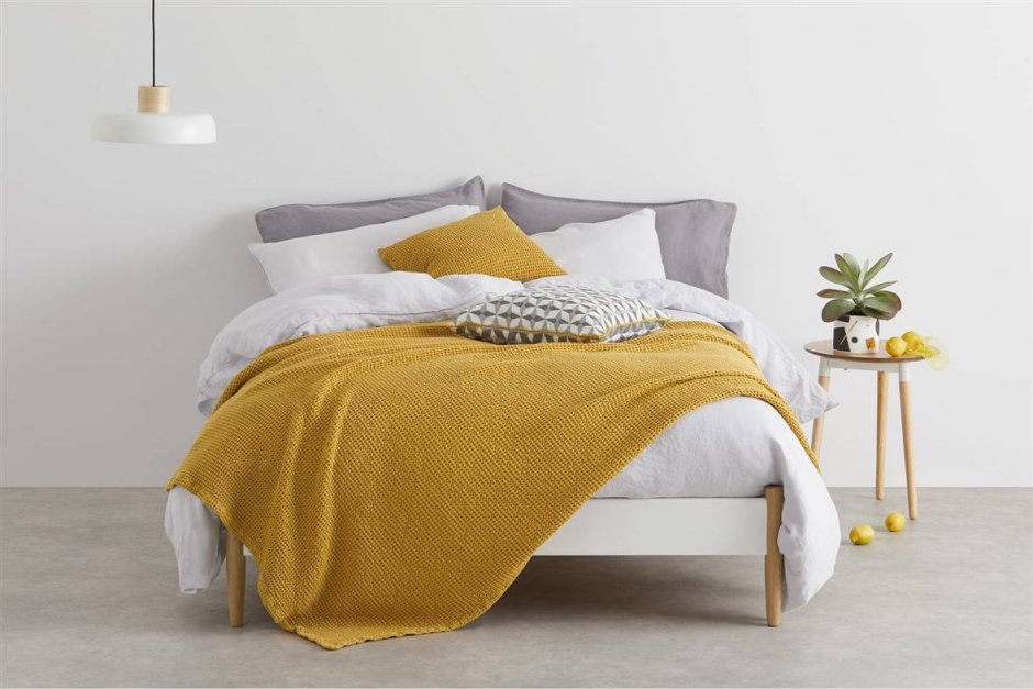 Белая кровать с желтыми подушками